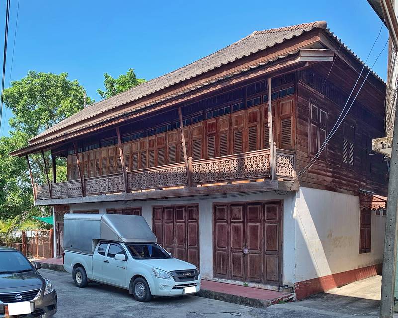 บ้านไม้สองชั้นหลังคาจั่ว ประตูบานเฟี้ยมไม้สีน้ำตาล ใต้ท้องฟ้าสีฟ้า